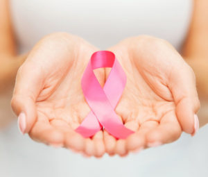 female hands cupped, close up, pink ribbon in hands, symbolizing breast cancer awareness month